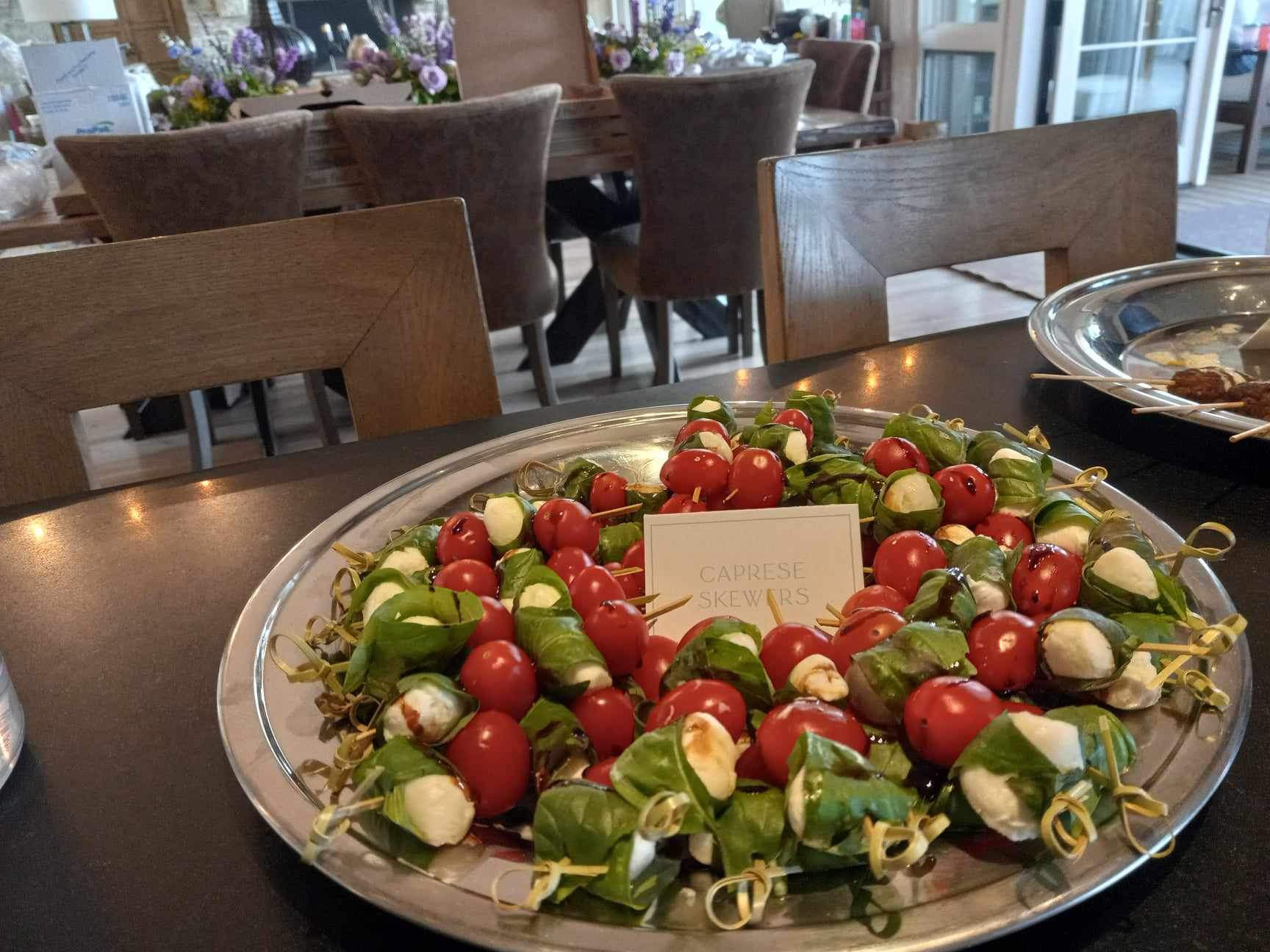 Caprese skewers with basil, mozzarella, and tomato on a silver tray