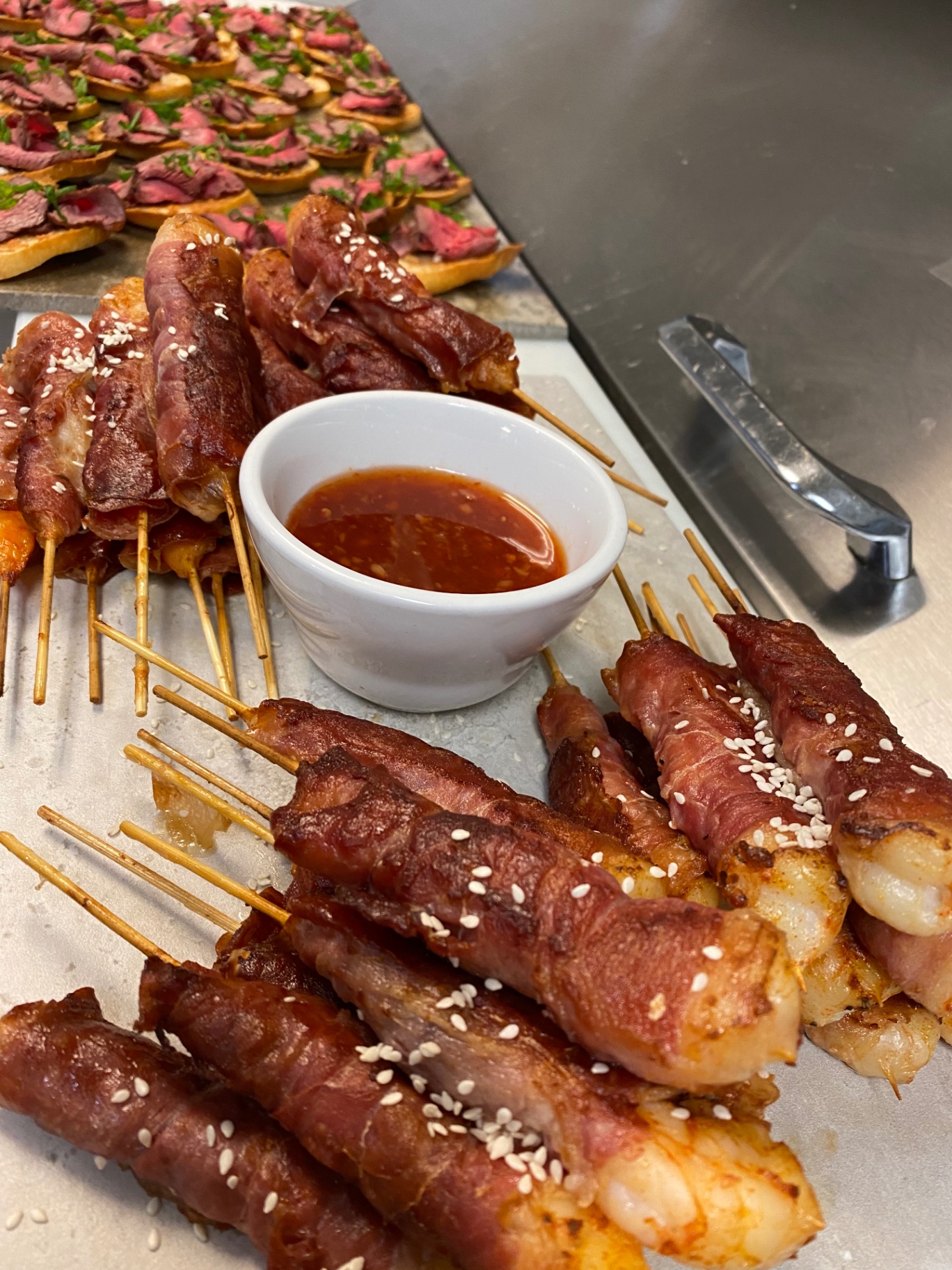 Prosciutto-wrapped shrimp skewers with sesame and sweet chili dipping sauce