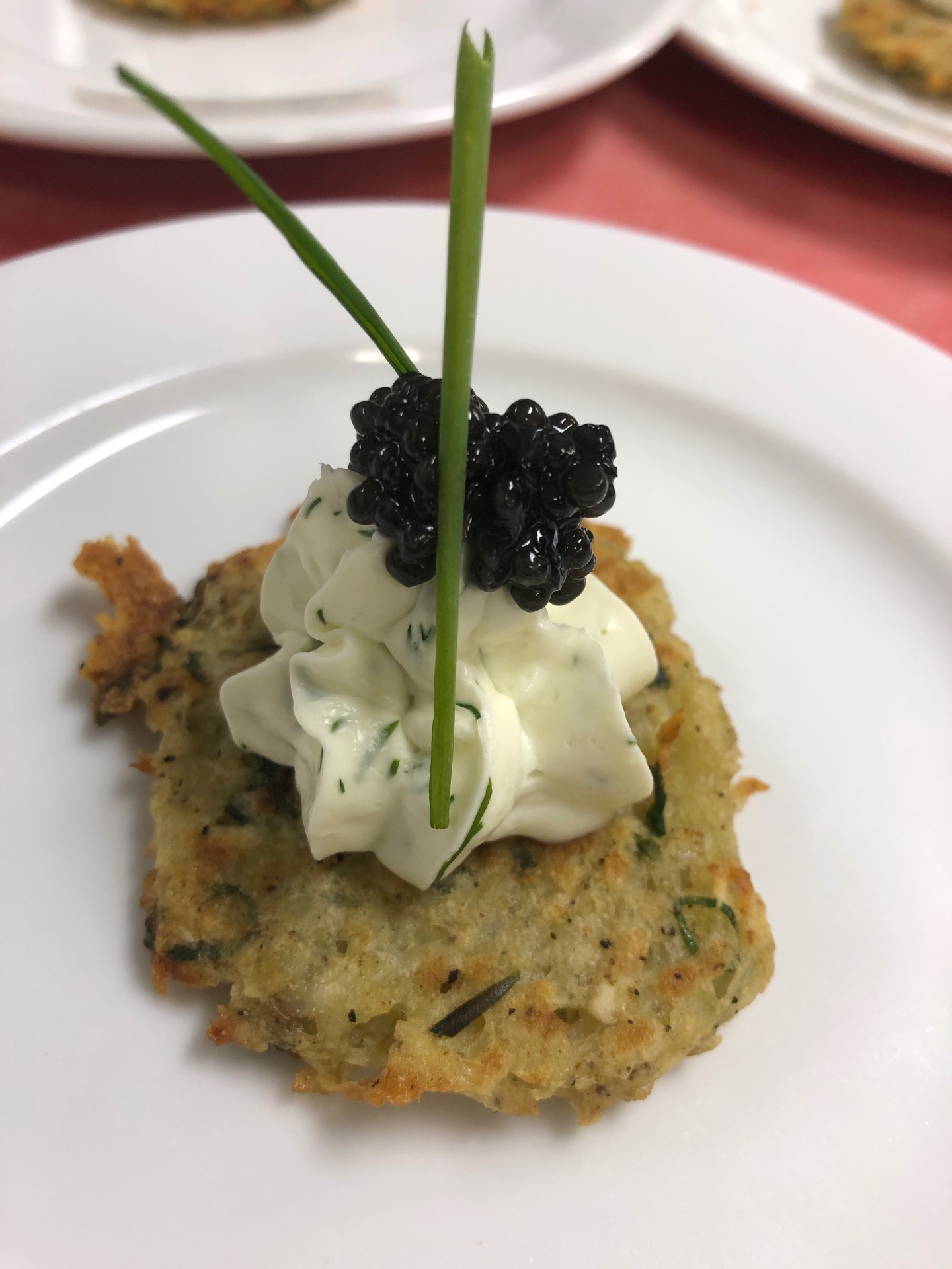 Potato latke topped with dill crème fraîche, caviar, and chive spears