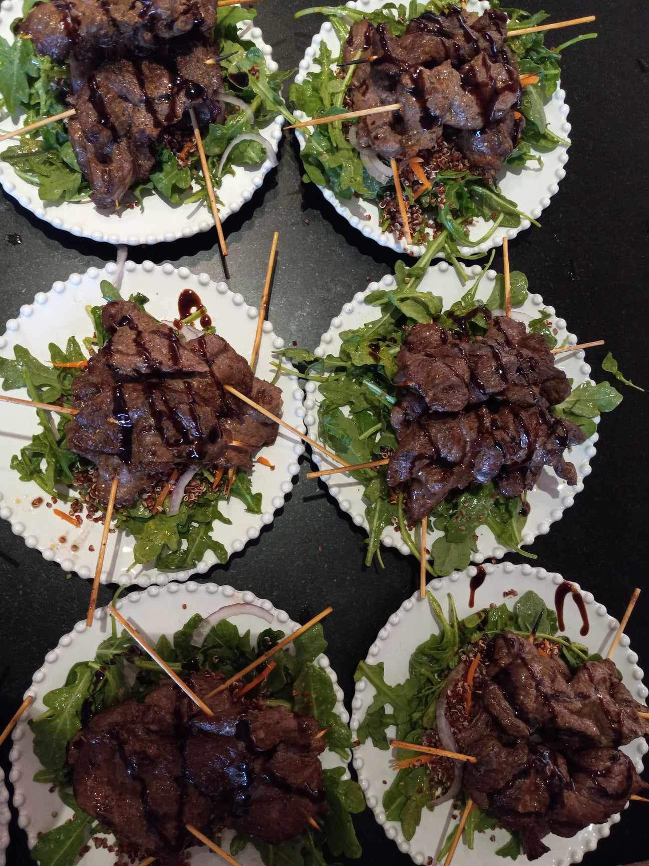 Balsamic-glazed steak skewers over arugula and red quinoa salads